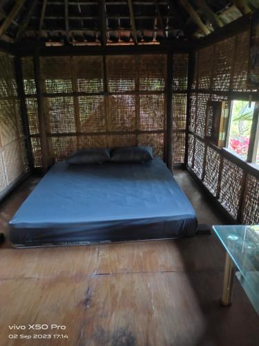 uma cama num quarto com piso em madeira em CLOVE GARDEN em Gitgit