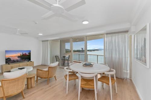 uma sala de jantar com mesa, cadeiras e janelas em Mariners North Holiday Apartments em Townsville