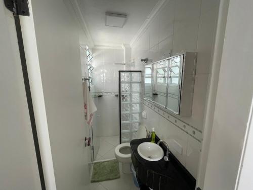 a white bathroom with a sink and a toilet at Apartamento Maré Mansa a 30 metros da praia Mansa em Caiobá com Wifi in Caiobá