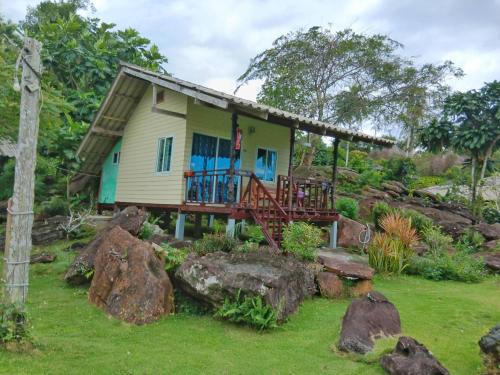 une petite maison avec une terrasse couverte et quelques rochers dans l'établissement The Ngam Kho Resort, à Ko Kood
