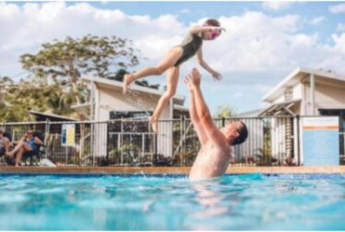 Un uomo e un bambino che saltano in una piscina di Discovery Parks - Broome a Broome