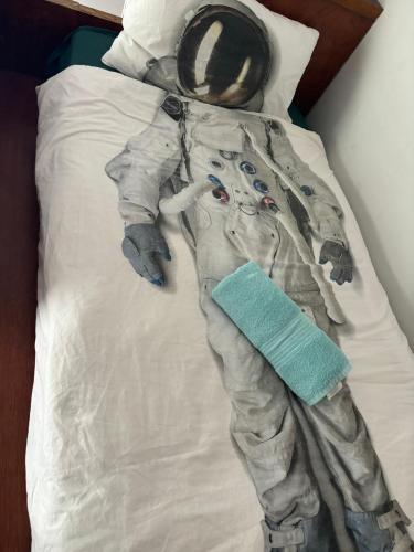 une personne en costume d'astronaute posant sur un lit dans l'établissement Mt Eden Tidy Bedroom rm7, à Auckland