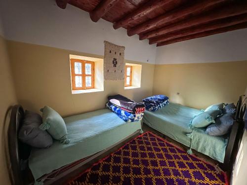 een kamer met 2 bedden met kussens en een tapijt bij Dar assounfou in Demnat