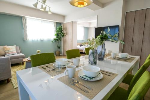 comedor con mesa blanca y sillas verdes en Premium Apartment Hotel Tokyo East, en Tokio