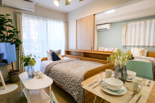 Habitación con 2 camas, mesa y TV. en Premium Apartment Hotel Tokyo East en Tokio