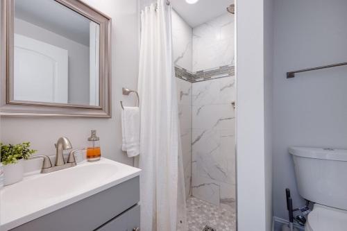 a white bathroom with a sink and a shower at Nash Luxe W King Suite & Fire Pit Fun & Games! in Nashville