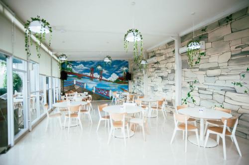 un restaurante con mesas y sillas y una pared de piedra en Cordela Inn R Sukamto Palembang, en Palembang