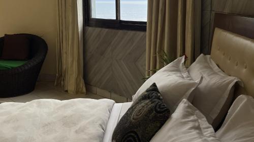 a bed with white pillows in a room with a window at Hotel les Polygones Kribi in Kribi