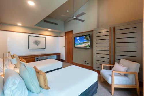 a bedroom with a bed and a couch and a tv at Yacht Club Villas on Hamilton Island by HIHA in Hamilton Island