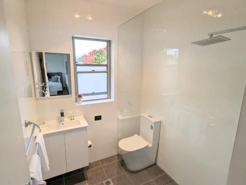 a bathroom with a toilet and a sink and a window at Lotus Stay Manly - Apartment 29E in Sydney