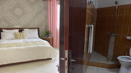 a bedroom with a bed and a shower and a toilet at Hotel les Polygones Kribi in Kribi