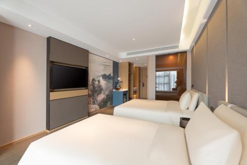 a bedroom with two beds and a flat screen tv at Atour Hotel Xian Bell Tower Yongningli in Xi'an