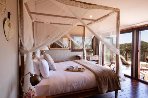 1 dormitorio con cama con dosel y balcón en Turon Gates - Mountain Retreat en Capertee