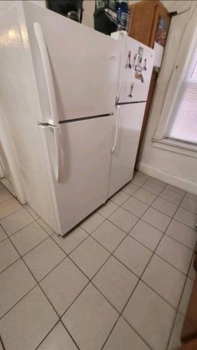 y cocina con nevera blanca y suelo de baldosa. en LARGE ROOM WITH SOFA BED FOR TWO PEOPLE near Manhattan on train, en Woodside