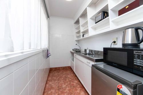 a kitchen with white walls and a black microwave at Aarangi Motel in Auckland