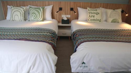 two beds in a hotel room with white sheets at 日日旅樹 Green Stay in Hualien City