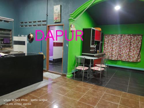 een keuken met een groene muur en een tafel en stoelen bij D’sireh homestay in Sik