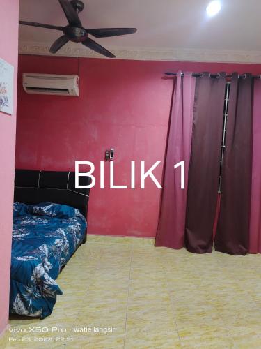 Cette chambre dispose d'un lit et d'un mur rouge avec le panneau blk. dans l'établissement D’sireh homestay, à Sik
