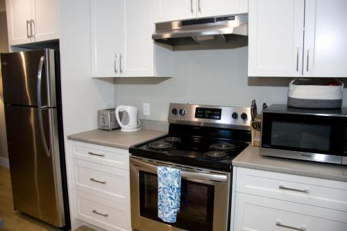 a kitchen with a stove and a refrigerator at M&M's Maple Bay Mountain Guesthouse in Duncan