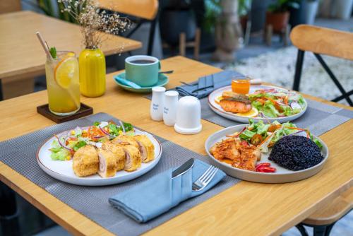 drie borden eten op een houten tafel bij Le Cap Hotel & Apartments and Gym in Da Nang