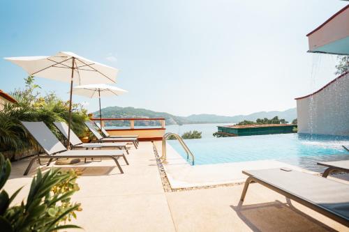 uma piscina com cadeiras e guarda-sóis junto à água em Villa del Pescador em Zihuatanejo