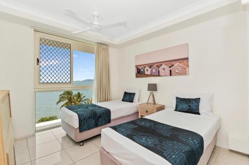 two beds in a room with a window at Mariners North Holiday Apartments in Townsville
