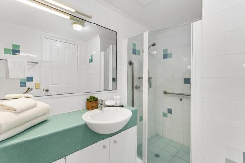 a white bathroom with a sink and a shower at Mariners North Holiday Apartments in Townsville