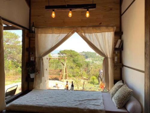 a bedroom with a bed with a large window at Romantic house on a pine hill Dalat in Xuan An