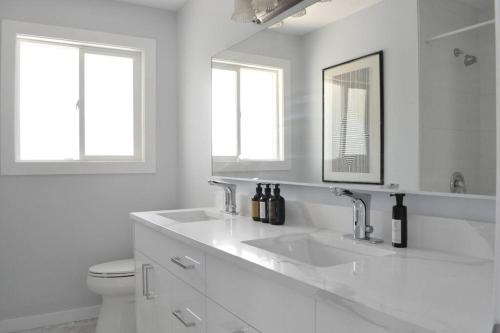 a white bathroom with two sinks and a toilet at 4 BR Home - Close by the River in Kamloops