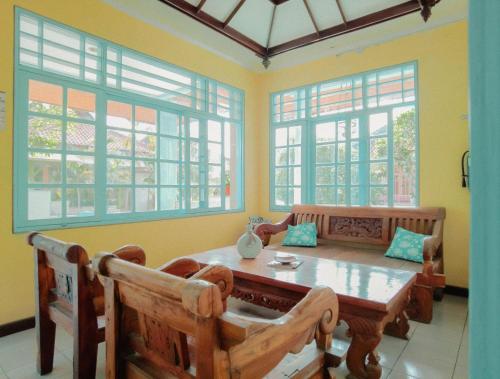 a dining room with a table and chairs and windows at BS Home in Kuta