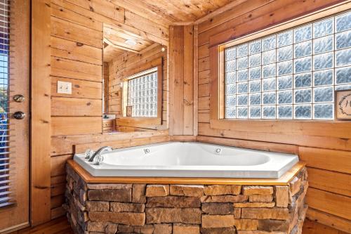 eine Badewanne in einem Holzbad mit Fenster in der Unterkunft Bearfoot Pines - True Log Cabin - Wi-Fi, Hot Tub, Fishing, Deck with views! - Mins to PF in Sevierville