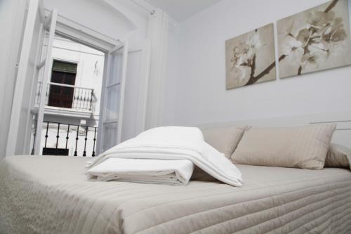 a white bed with a blanket on top of it at Apartamentos Casamonteymar Bas-Ser in Vejer de la Frontera