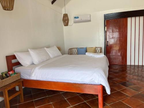 um quarto com uma cama grande e lençóis brancos em Solimar Seaside Cabanas em Tambobong