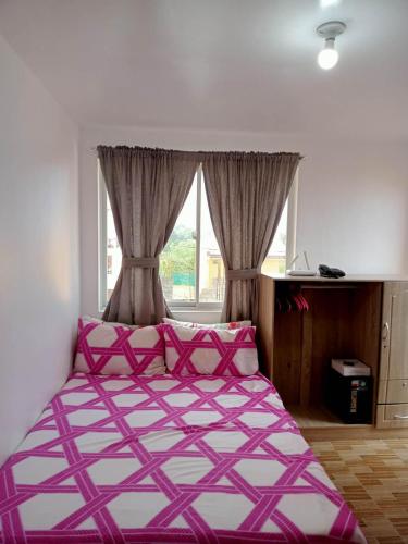a bedroom with a large bed with pink and white sheets at Noana Crib in Davao City