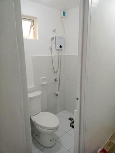 a white bathroom with a toilet and a shower at Noana Crib in Davao City