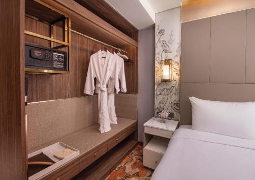 a bedroom with a bed and a robe on a rack at SAMALA Hotel Bangkok in Bangkok
