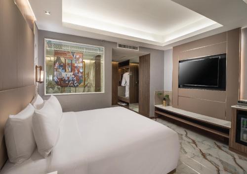a bedroom with a white bed and a flat screen tv at SAMALA Hotel Bangkok in Bangkok