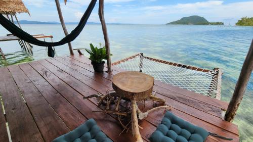 a wooden deck with a table and chairs on the water at Mansuar Raja Ampat Bungalows in Kri