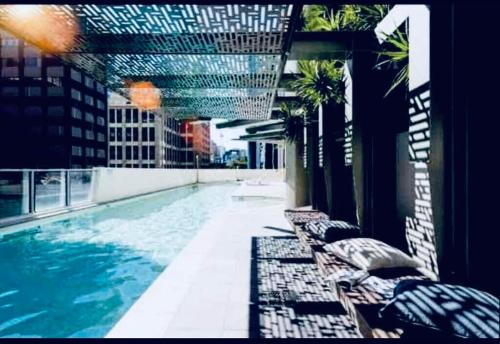 ブリスベンにあるBrisbane Break Panoramic River Views Free Parkingの建物内のスイミングプール(長椅子付)