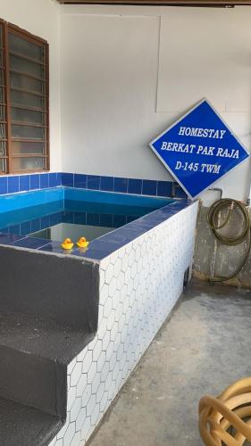 a swimming pool with a sign on the wall at Berkat Pak Raja Homestay Mergong Alor Setar 
