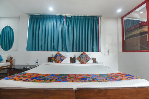 1 dormitorio con 1 cama grande y cortinas azules en FabExpress Stargaze Beach, en Anjuna