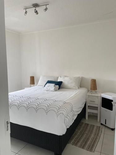 a bedroom with a large white bed with a television at Dmn City Apartment at Junction in Windhoek