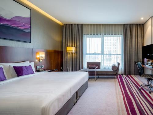 a hotel room with a large bed and a desk at Flora Al Barsha Hotel At The Mall in Dubai