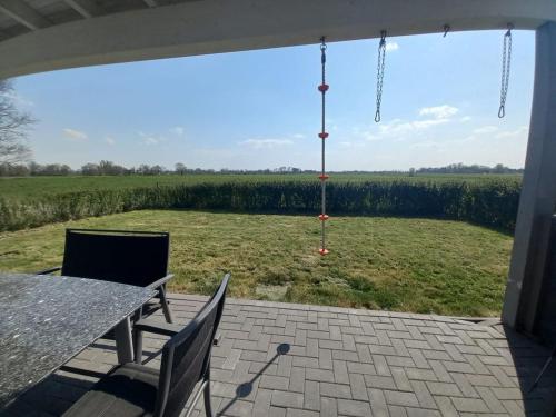 een patio met een tafel en stoelen en uitzicht op een veld bij Ferienhaus Familiennest in Sehestedt