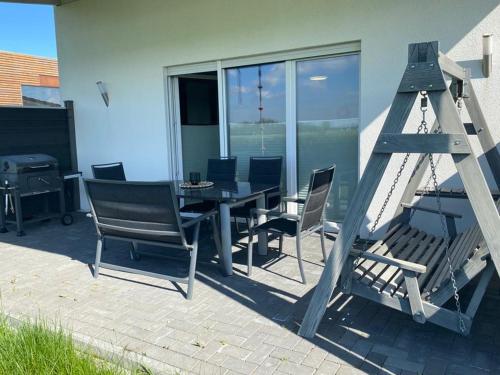 een patio met een tafel en stoelen en een ladder bij Ferienhaus Familiennest in Sehestedt