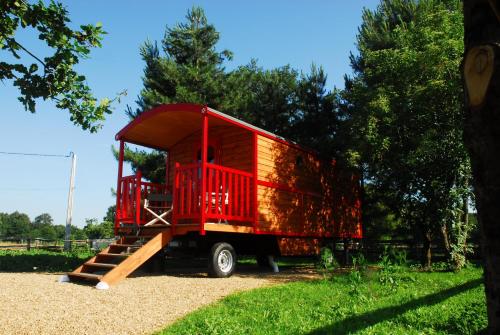 um camião vermelho com uma casa de madeira na parte de trás em Gypsy Nature B&B em Jumelles