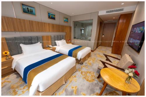 a hotel room with two beds and a table at Phú Long Tam Kỳ Hotel & Restaurant in Tam Ky