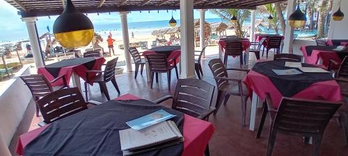 a restaurant with tables and chairs and the beach at Hotel Universal Beach in Hikkaduwa
