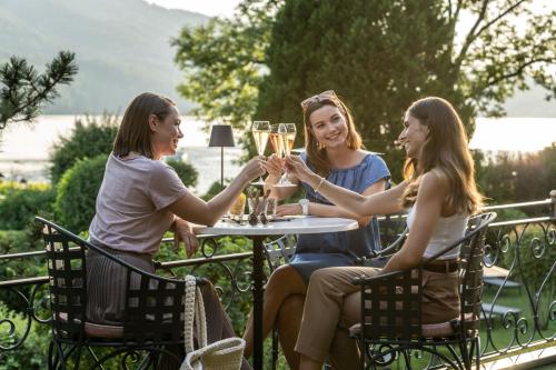 three women sitting around a table with glasses of champagne at Waldhof Fuschlsee Resort in Fuschl am See