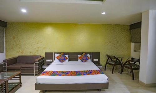 een slaapkamer met een groot bed en een bank bij FabHotel Midland in Bhopal